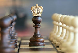A brown pawn with a crown stands prominently on a chessboard, symbolizing strategic play.