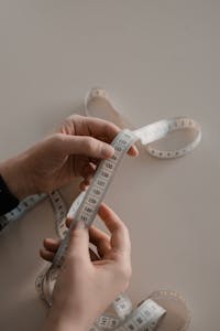Close-up of hands holding a white measuring tape, ideal for sewing concepts.