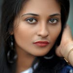 Close-up portrait of a South Asian woman with a serene expression, wearing earrings and a bracelet, captured in Kozhikode, India.