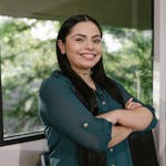 Portrait of a confident businesswoman standing with arms crossed in modern office space.