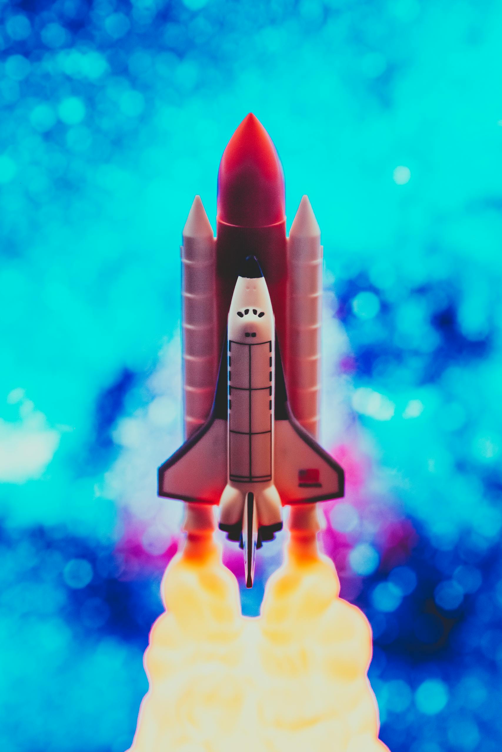 Colorful toy rocket launch with a vivid blue bokeh background, showcasing energy and excitement.